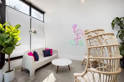 Lounge corner with a sofa and a neon flamingo sign at Nala’s Party Room in Irving Park